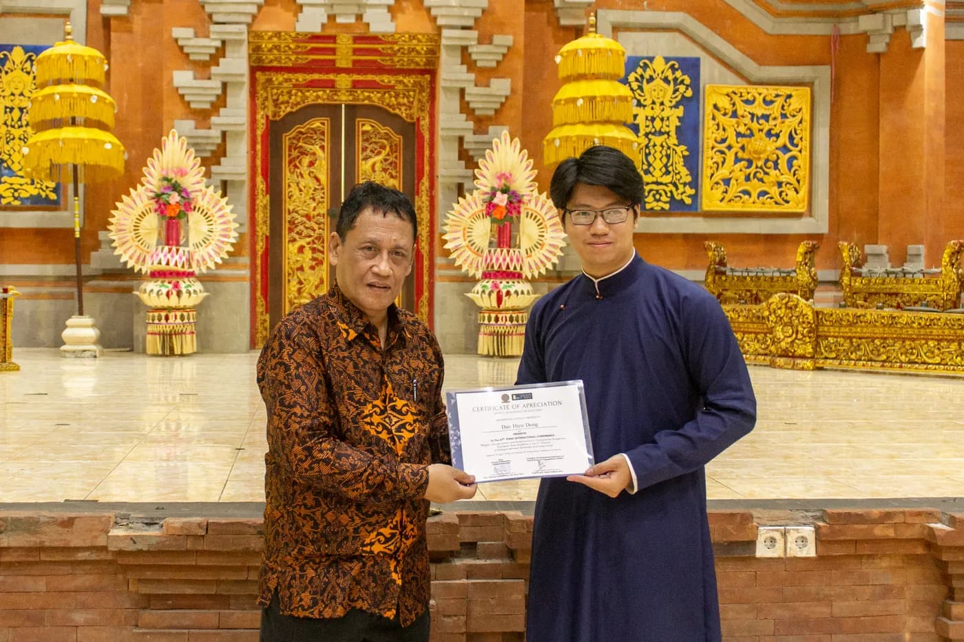 Hình ảnh Co-founder Cờ Thủy TInh Châu chụp hình cùng chủ tịch IFSSO tại Hội nghị quốc tế lần thứ 27 của Liên đoàn Các Tổ chức Khoa học Xã hội Thế giới (IFSSO) , được tổ chức tại Đại học Udayana (Bali, Indonesia).