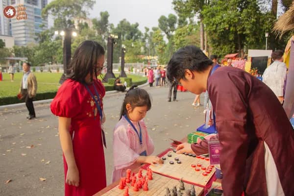 Hình ảnh Team Cờ Thủy Tinh Châu hướng dẫn khách tham dự nhỏ tuổi gồm mẹ và bé trải nghiệm Cờ Thủy Tinh Châu tại Dinh Độc Lập trong chương trình Họp mặt người Việt Nam ở nước ngoài mừng Xuân Bính Ngọ 2026