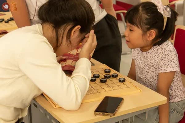 Hình ảnh bạn học sinh Trường Vietnam Australia International School hướng dẫn em nhỏ chơi Cờ Thủy Tinh Châu trong sự kiện VAS OMLYMPIC 2026