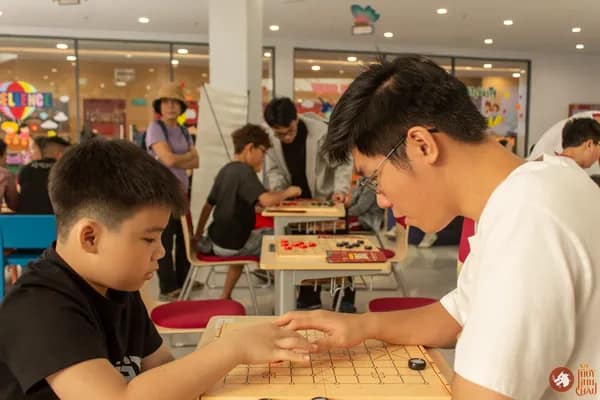 Hình ảnh bạn học sinh Trường Vietnam Australia International School hướng dẫn em nhỏ chơi Cờ Thủy Tinh Châu trong sự kiện VAS OMLYMPIC 2026