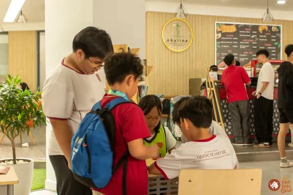 Hình ảnh bạn học sinh Trường Vietnam Australia International School hướng dẫn em nhỏ chơi Cờ Thủy Tinh Châu trong sự kiện VAS OMLYMPIC 2026